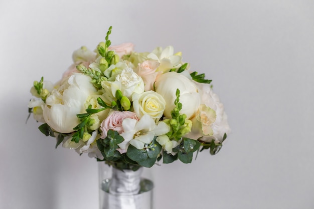 Buquê de casamento em um vaso de vidro nas escadas perto da parede.