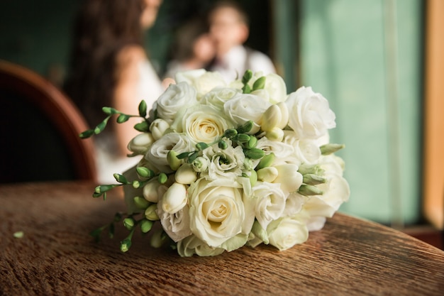 Buquê de casamento em uma mesa de madeira. Bouquet de noiva de frésia e rosas