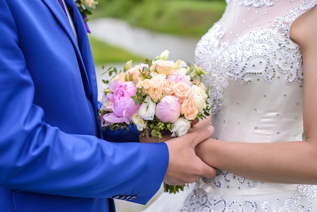 Buquê de casamento nas mãos da noiva e do noivo