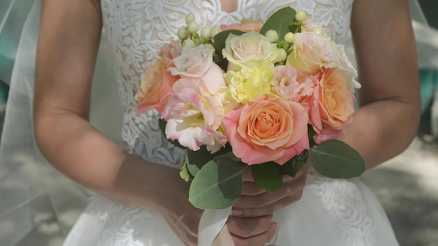 Buquê de casamento nas mãos da noiva rosas coloridas do dia ensolarado closeup