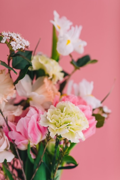 Buquê de cravos peônia tulipas rosas e narcisos em um fundo rosa closeup