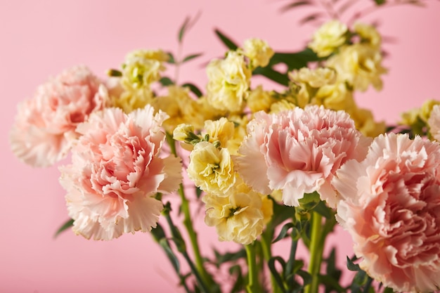 Buquê de cravos rosa e matthiola amarela com conceito de design de ramos verdes de saudação de feriado ...