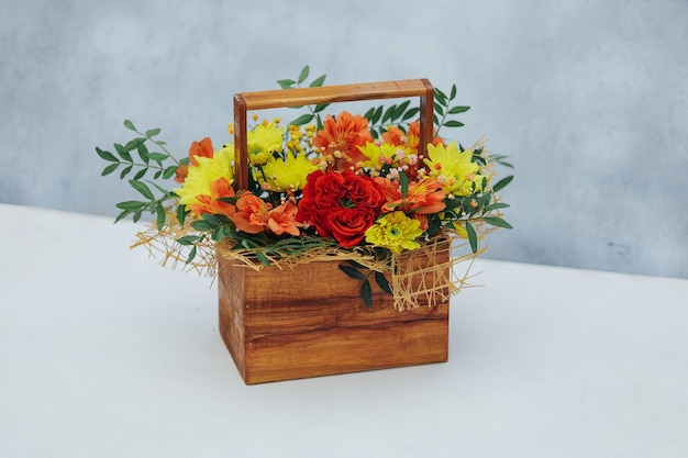 Buquê de crisântemo peônia rosa e alstroemeria em uma caixa de presente de madeira em um fundo cinza disponível em vermelho laranja e amarelo