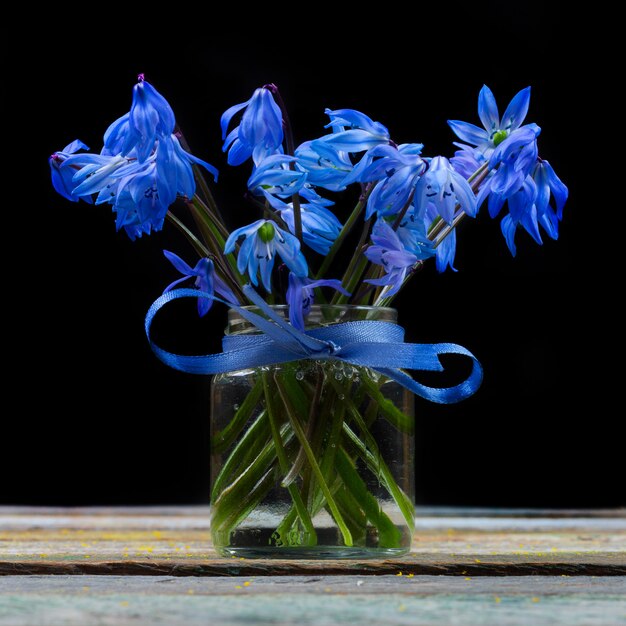 Buquê de flores de bluebell em um vaso na mesa em um fundo preto closeup