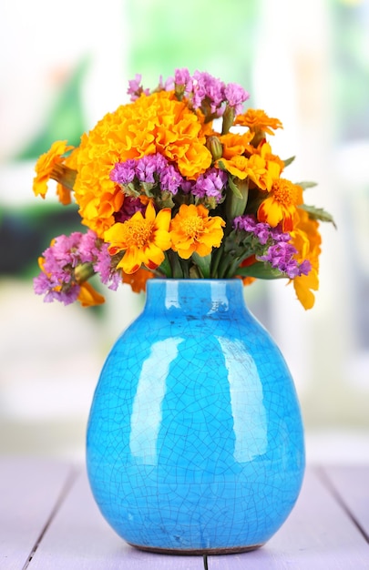 Buquê de flores de calêndula em vaso na mesa de madeira no fundo natural