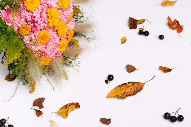 Buquê de flores de outono ásteres rosa e amarelo e folhas de outono e ervas em fundo rosa pastel