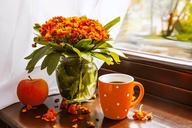 Buquê de flores de primavera laranja na janela à luz do sol Copa laranja e maçã vermelha