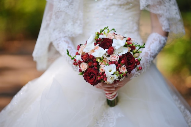Buquê de flores de rosas brancas e vermelhas nas mãos da noiva