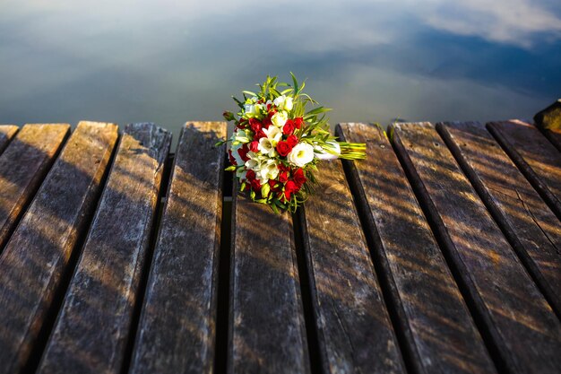 Buquê de flores de rosas vermelhas e brancas na ponte de madeira com sol da tarde