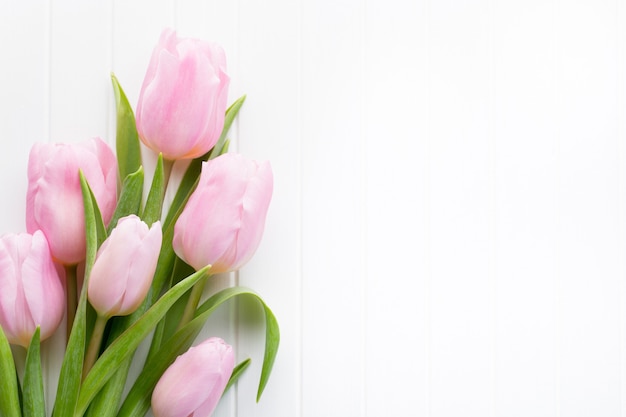 Buquê de flores de tulipa rosa fresca na prateleira em frente à parede de madeira