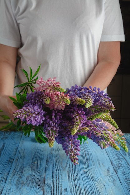 Foto buquê de flores de verão nas mãos femininas contra uma superfície de madeira