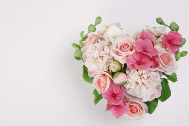 Buquê de flores em forma de um coração em uma superfície branca. . dia dos namorados, o conceito de casamento.