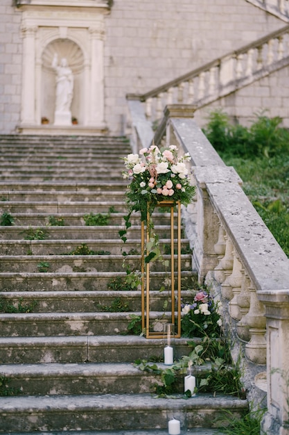 Buquê de flores em um alto suporte de metal em degraus de pedra antigos