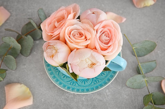 Buquê de flores em um copo sobre uma mesa cinza