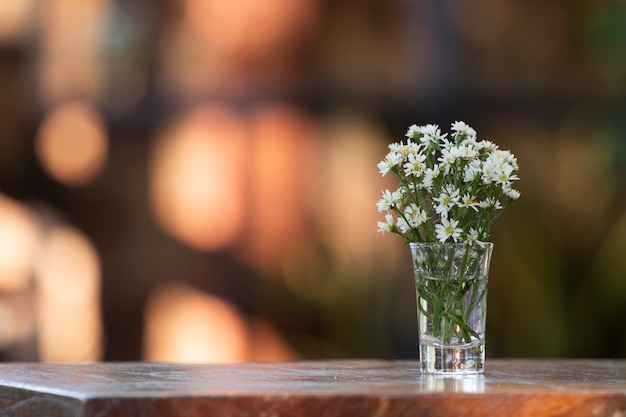 Buquê de flores em um vaso na mesa de madeira. Com jardim em segundo plano.