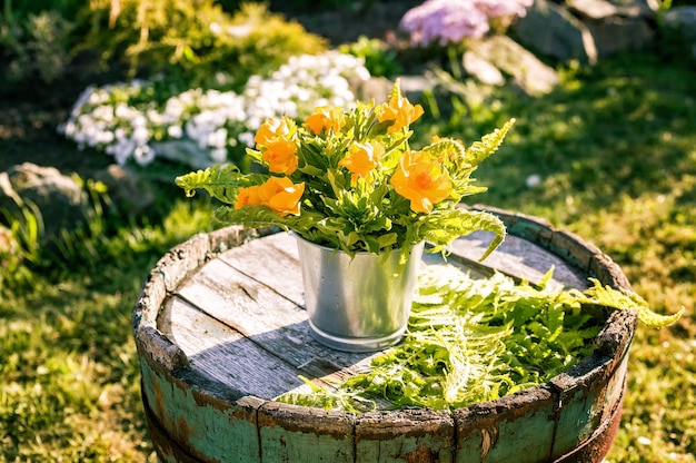 Buquê de flores em vasos de lata em um velho barril de madeira.