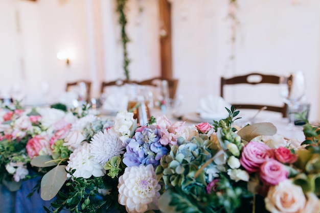 buquê de flores frescas de rosa, brancas e azuis em cima da mesa do restaurante
