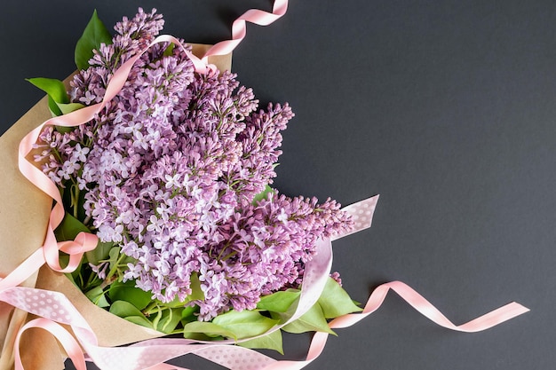 Buquê de flores lilás com fitas em um fundo escuro. cartão postal com lugar para texto.