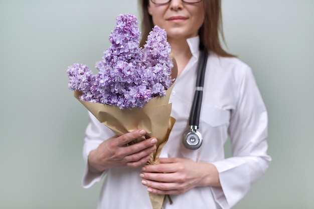 Buquê de flores lilás nas mãos da médica. Celebração, presente, respeito e amor