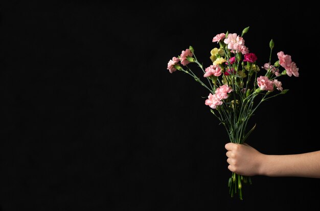 Buquê de flores na mão do menino com copyspace preto. Conceito de dia das mães