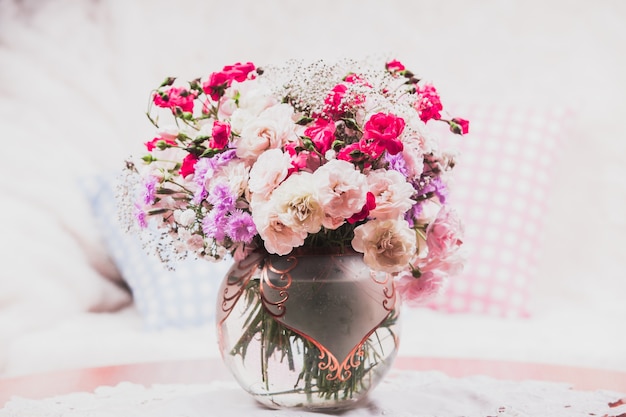 Foto buquê de flores na mesa perto do sofá com um travesseiro