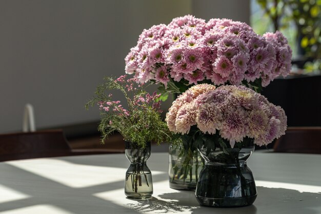 Buquê de flores rosa crisântemo rosa turva em vaso de vidro em cima da mesa.