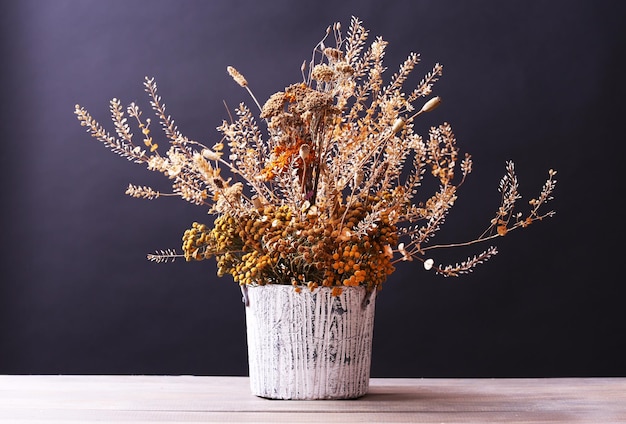 Buquê de flores secas em vaso na mesa e fundo escuro