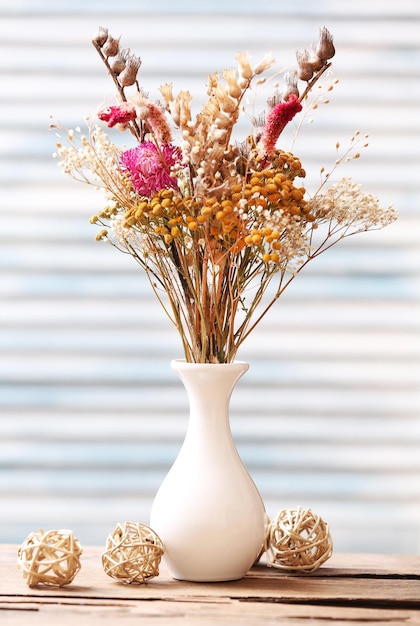 Buquê de flores secas em vaso sobre fundo de pranchas de cor