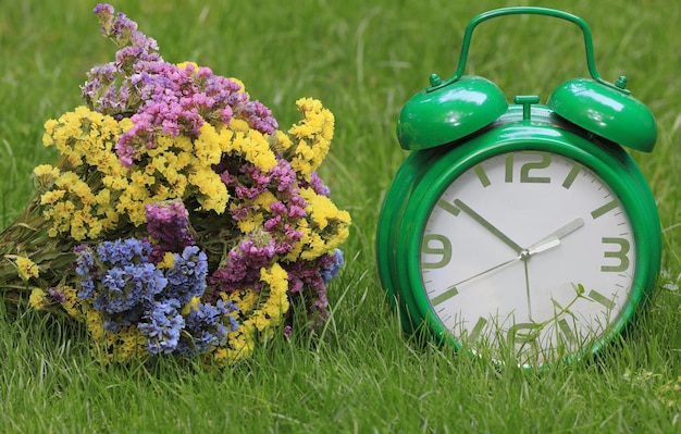 buquê de flores silvestres e um despertador na grama