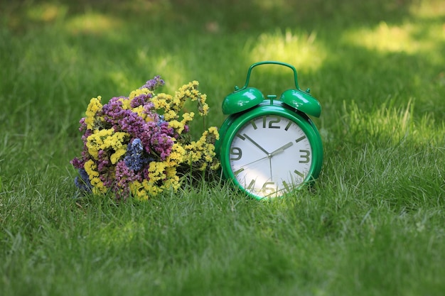 Buquê de flores silvestres e um despertador na grama