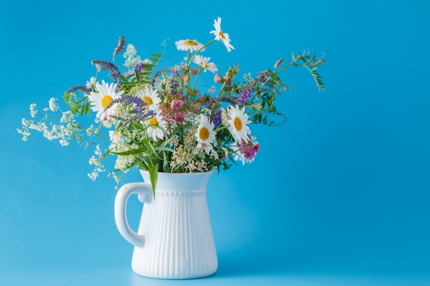 Buquê de flores silvestres em jar no fundo azul liso