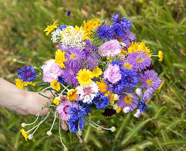 Buquê de flores silvestres misturadas na mão de uma mulher