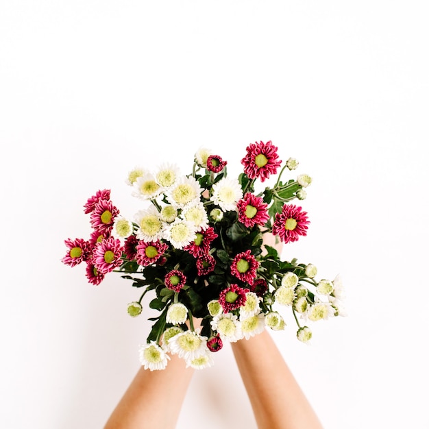 Buquê de flores silvestres nas mãos de uma garota na superfície branca