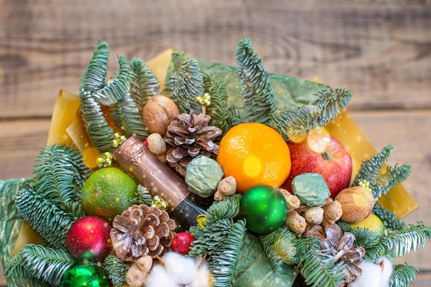 Foto buquê de galhos de uma árvore de natal, maçãs, doces, laranja, algodão e, nozes