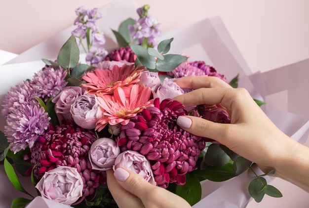 Buquê de gérberas de rosas e crisântemos frescos com mãos femininas.