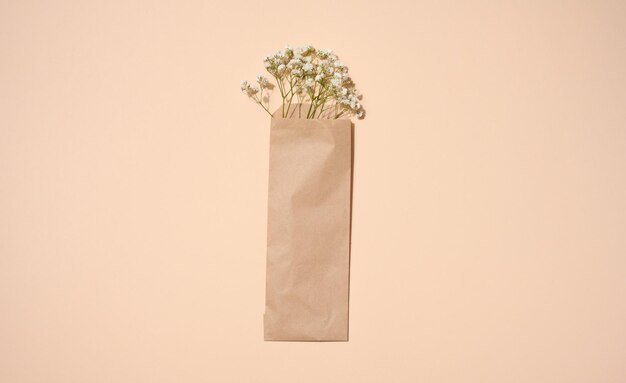 Buquê de gypsophila branco em um saco de papel kraft marrom em uma vista superior de fundo bege