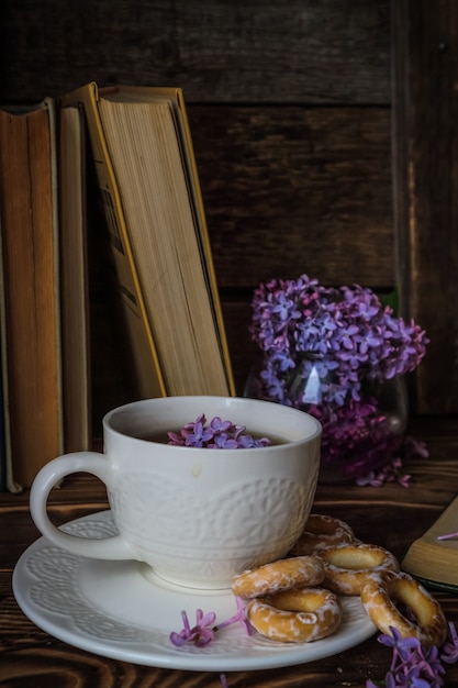 buquê de lilases e uma xícara de chá branca em um fundo de madeira