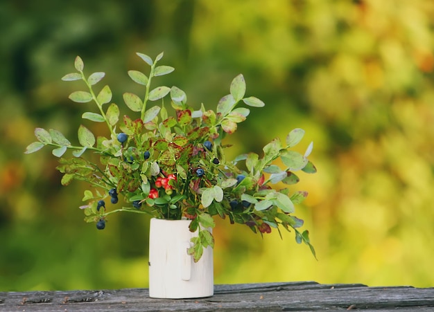 Buquê de mirtilo e cranberry maduros da floresta selvagem em um vaso de madeira.