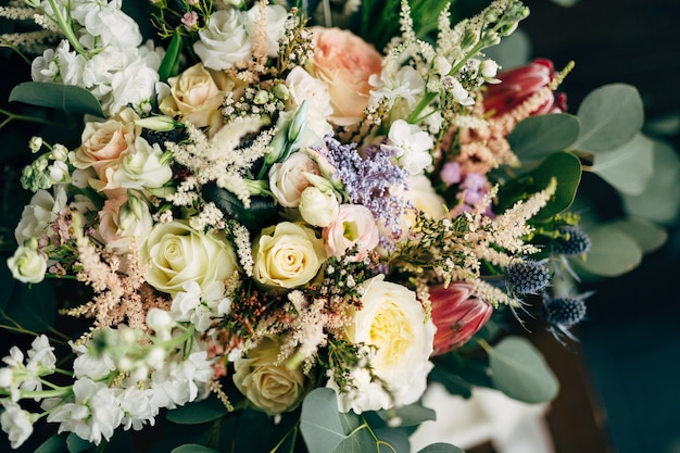 Buquê de noiva com ramos de rosas brancas e creme de eucalipto protea eryngium e delphinium