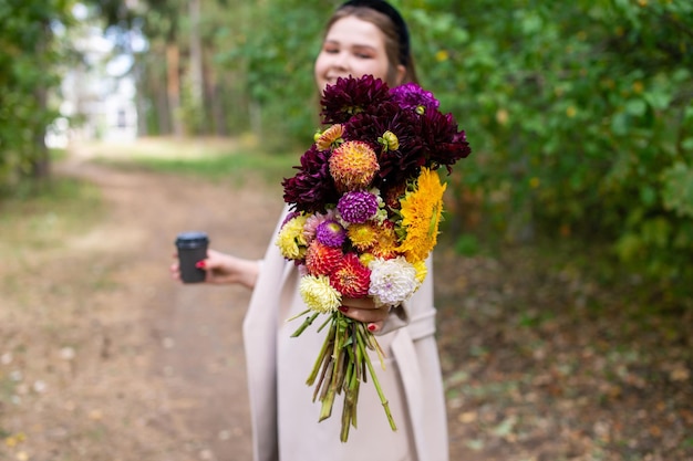 Buquê de outono de flores nas mãos de uma linda garota