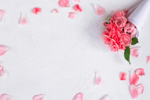 Buquê de pequenas rosas cor de rosa em papel sobre a mesa Vista de cima