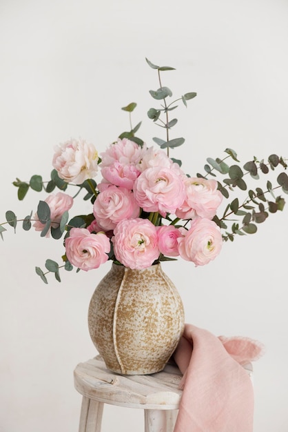 Buquê de primavera de peônias e ranúnculo em uma imagem de foco seletivo de vaso bege