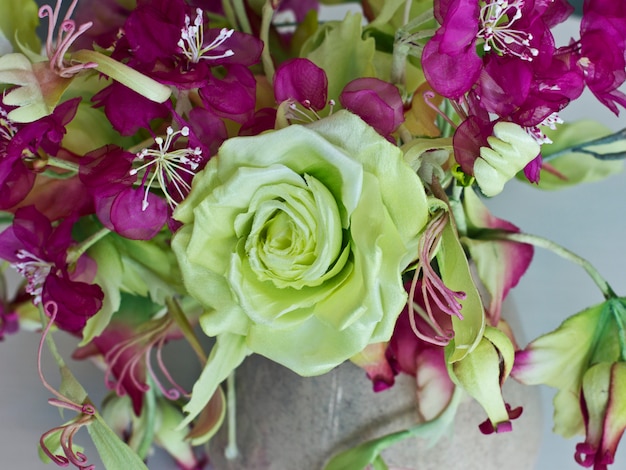 Buquê de rosas amarelas com flores vermelhas com botões em um vaso em uma mesa branca