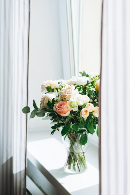 Buquê de rosas brancas e rosas verdes e outras flores no peitoril da janela em casa