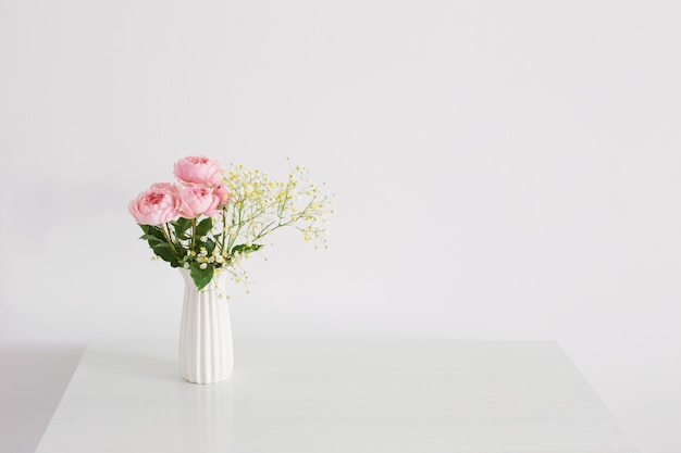 Buquê de rosas cor de rosa em vaso de cerâmica branca sobre fundo branco