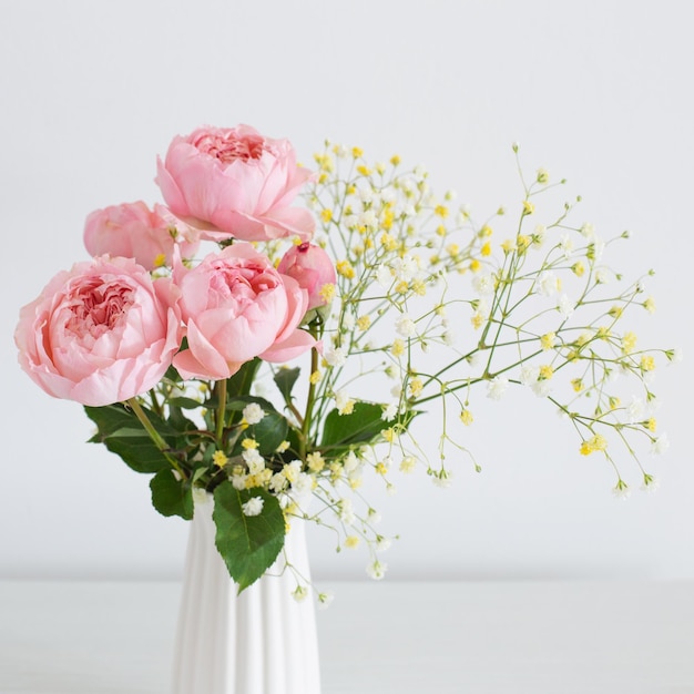 Buquê de rosas cor de rosa em vaso de cerâmica branca sobre fundo branco