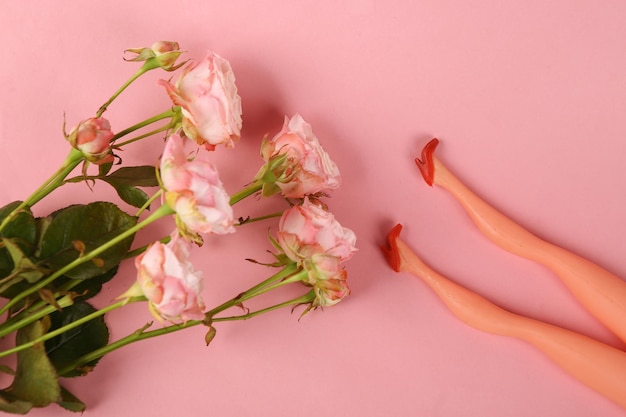 Buquê de rosas e pés de boneca em fundo rosa pastel