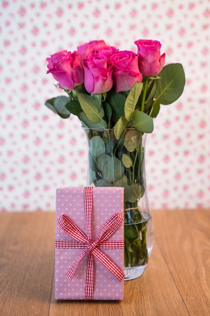 Buquê de rosas em um vaso com rosa presente encostado nele