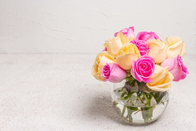 Buquê de rosas frescas multicoloridas em um vaso. O conceito festivo para casamentos, aniversários, dia 8 de março, dia das mães ou dos namorados. Cartão de felicitações, fundo claro
