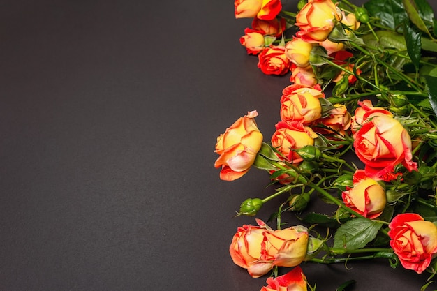 Buquê de rosas laranja brilhantes sobre fundo preto de pedra.